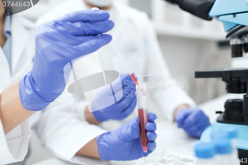 Image of close up of scientists filling test tube in lab