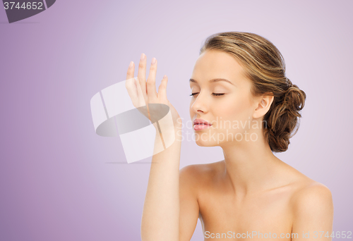 Image of woman smelling perfume from wrist of her hand