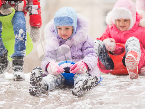 Image of Two cheerful girls are rolling hills with each other with icy hill