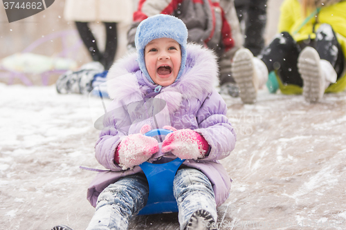 Image of Five-year girl with a happy cry slipping ice slides
