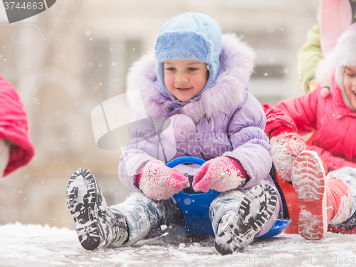 Image of Happy little girl getting ready to roll down the icy hill