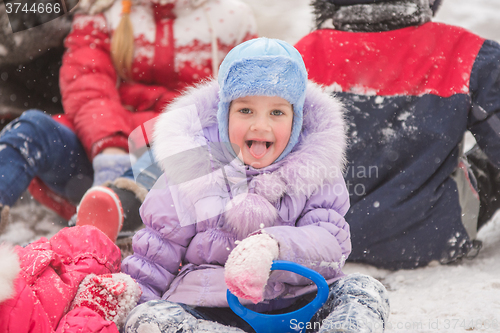Image of  Five-year girl sitting in the snow surrounded by other children