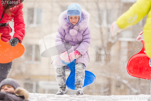 Image of Funny five-year girl runs up to roll down a icy hill