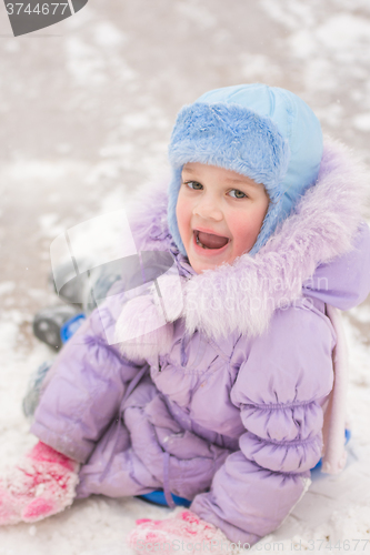 Image of Funny five-year girl sitting rolled down an ice slide