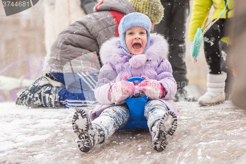 Image of Five-year girl fun screaming slides down the icy hill