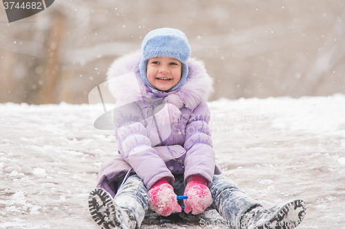 Image of Joyful five years girl rolls down from the icy hill