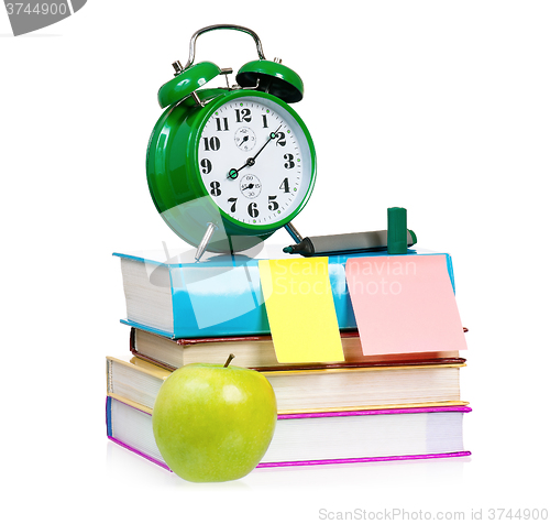 Image of  Big green alarm clock with books and apple 