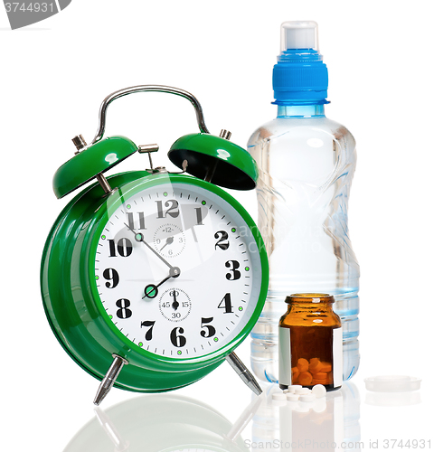 Image of Big alarm clock with bottle of water and pills