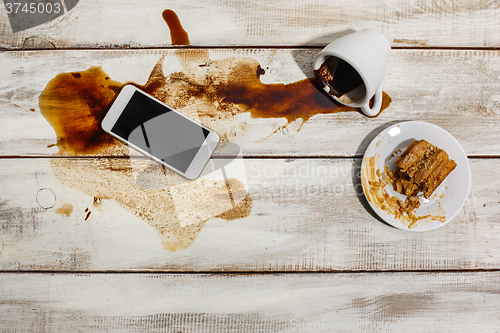 Image of Cup of coffee spilled on wooden table