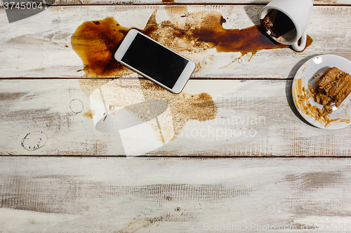 Image of Cup of coffee spilled on wooden table