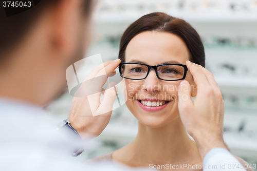 Image of optician putting glasses to woman at optics store