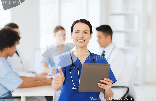 Image of happy doctor with tablet pc over team at clinic