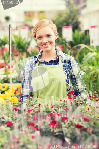 Image of happy woman with flowers in greenhouse