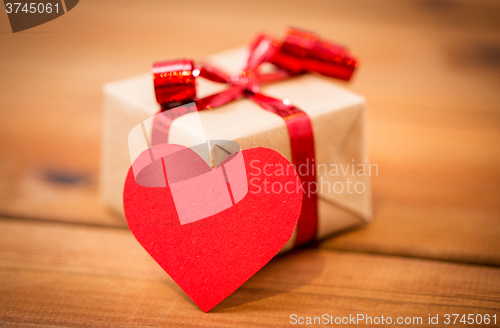 Image of close up of gift box and heart shaped note on wood