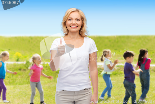 Image of woman showing thumbs up over group of little kids