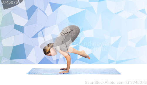 Image of woman making yoga in crane pose on mat