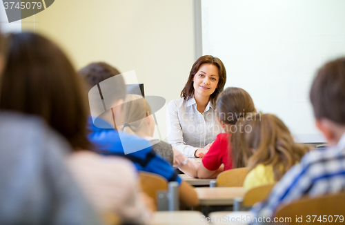 Image of group of school kids raising hands in classroom