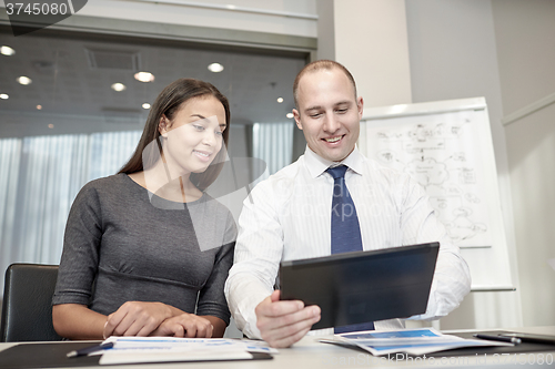 Image of smiling businesspeople with tablet pc in office