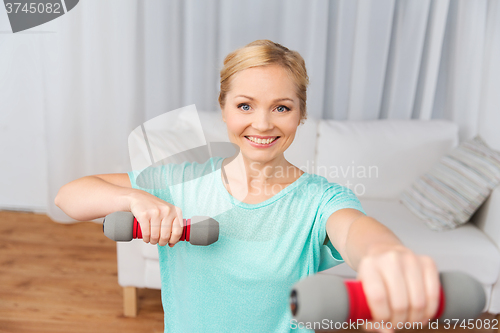 Image of woman exercising with dumbbells on mat at home