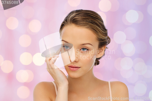 Image of young woman applying cream to her face