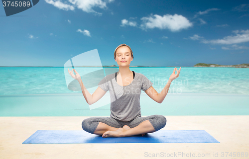 Image of woman making yoga meditation in lotus pose on mat