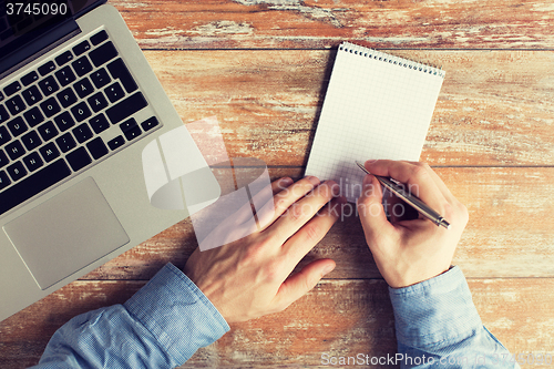 Image of close up of male hands with laptop and notebook