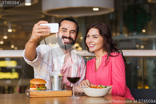 Image of couple taking selfie by smartphone at restaurant