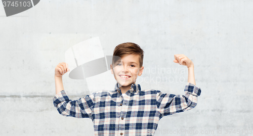 Image of happy boy in checkered shirt showing strong fists