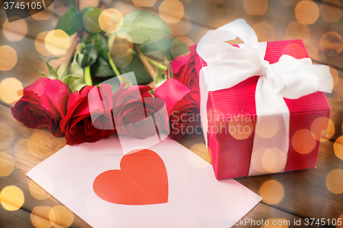 Image of close up of gift box, red roses and greeting card