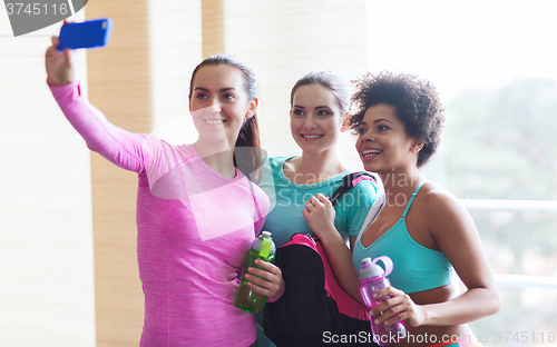 Image of happy women with smartphone taking selfie in gym