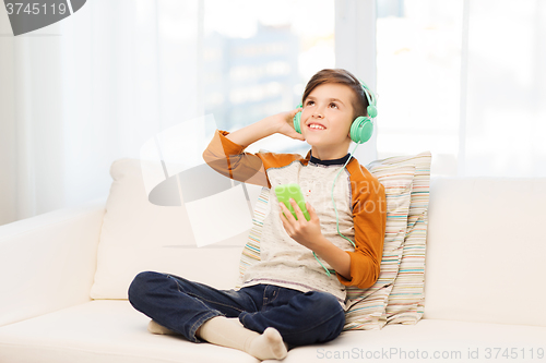 Image of happy boy with smartphone and headphones at home