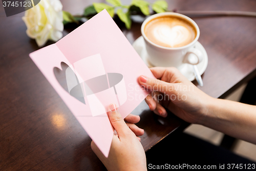 Image of close up of woman reading greeting card and coffee