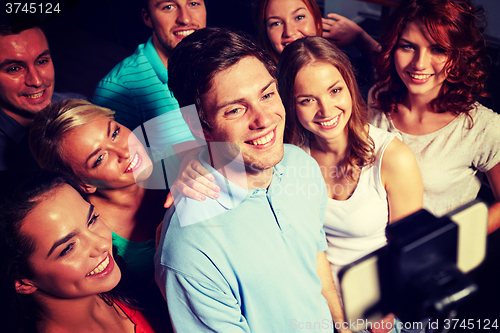 Image of friends with smartphone taking selfie in club