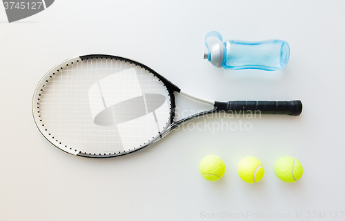 Image of close up of tennis racket with balls and bottle