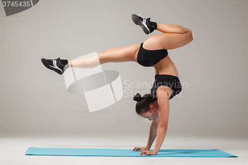 Image of Beautiful sporty girl standing in acrobat pose or yoga asana