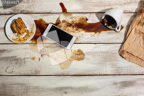 Image of Cup of coffee spilled on wooden table