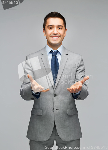 Image of happy businessman in suit showing empty palms