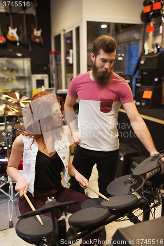 Image of man and woman with drum kit at music store