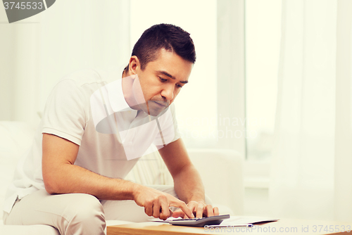Image of man with papers and calculator at home