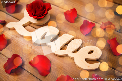 Image of close up of word love cutout with red rose on wood