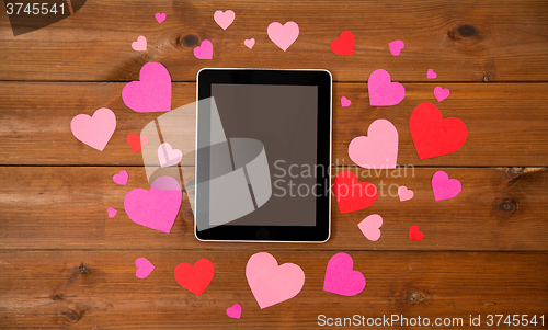 Image of close up of tablet pc and hearts on wood