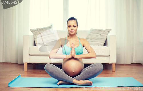 Image of happy pregnant woman meditating at home