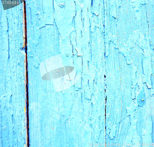 Image of dirty stripped paint in the blue wood door and rusty nail