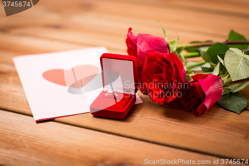 Image of close up of diamond ring, roses and greeting card