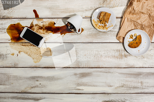 Image of Cup of coffee spilled on wooden table