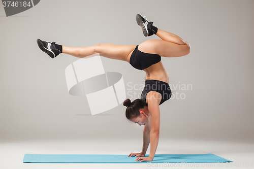 Image of Beautiful sporty girl standing in acrobat pose or yoga asana