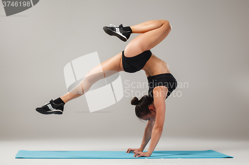 Image of Beautiful sporty girl standing in acrobat pose or yoga asana