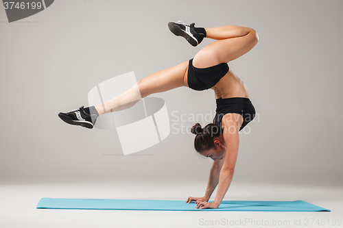 Image of Beautiful sporty girl standing in acrobat pose or yoga asana