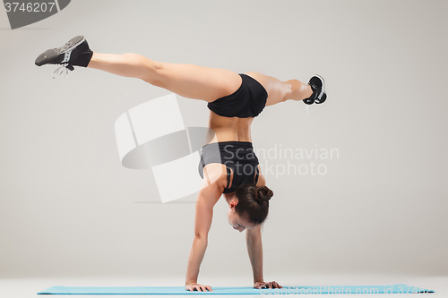 Image of Beautiful sporty girl standing in acrobat pose or yoga asana