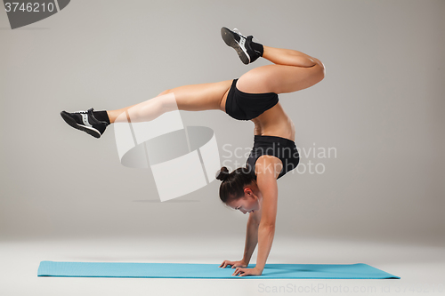 Image of Beautiful sporty girl standing in acrobat pose or yoga asana